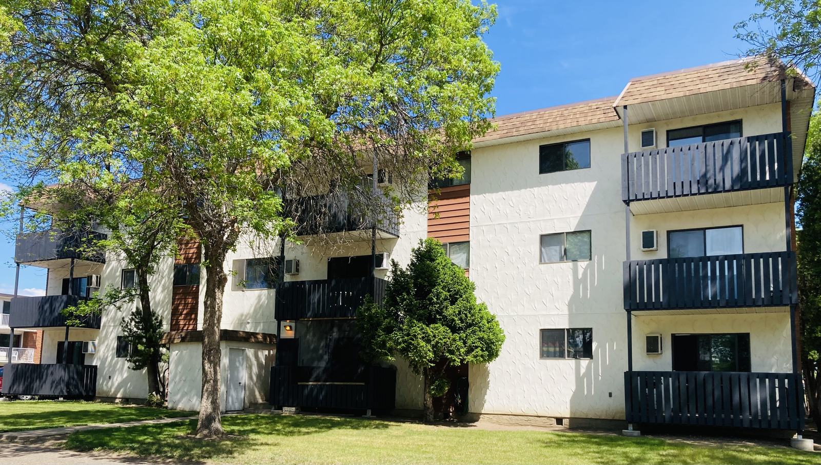 College Drive apartment building on a summer afternoon, mature trees and lawn