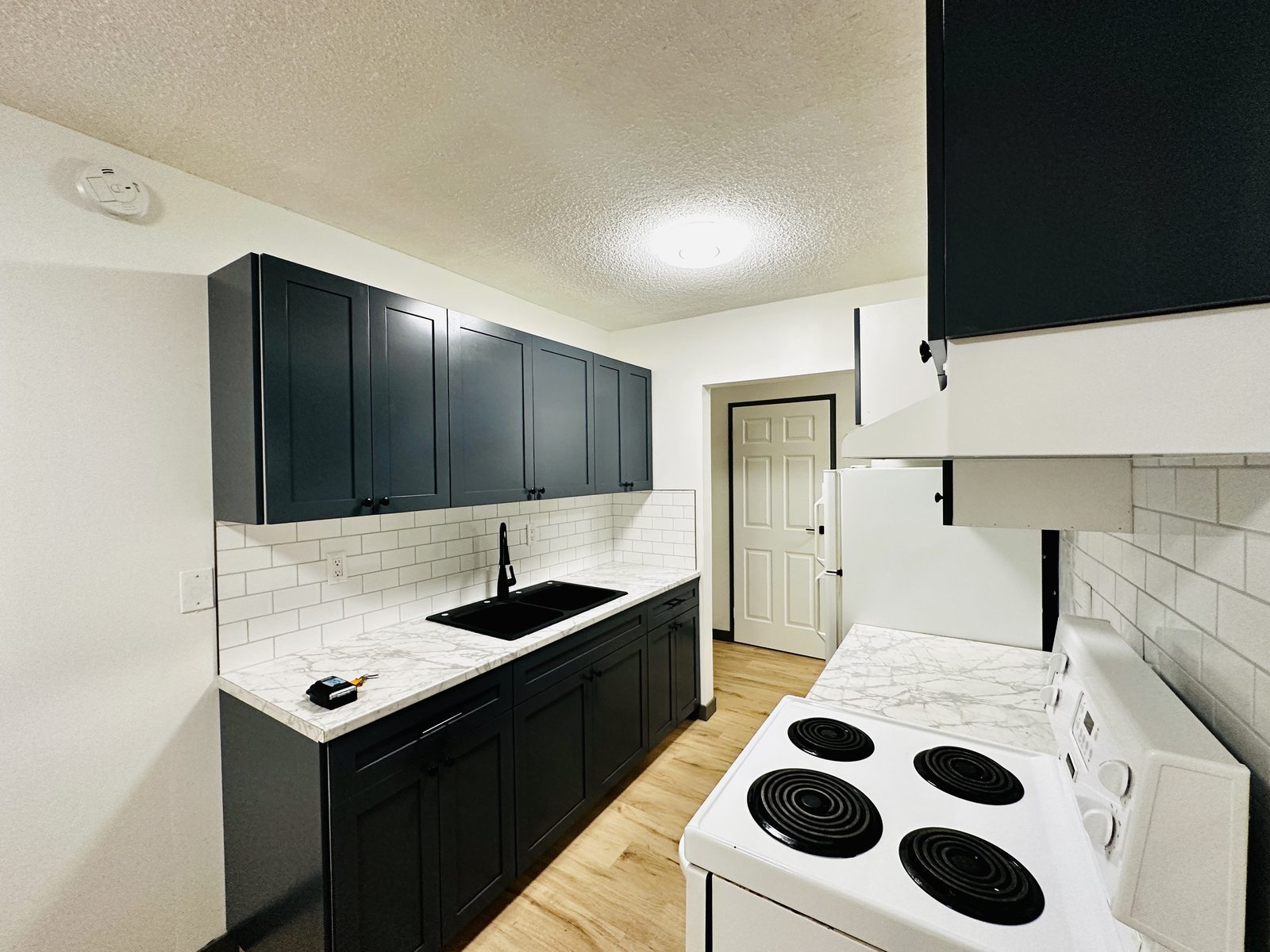 Renovated kitchen at Upland — dark shaker cabinets, subway tile, new counters